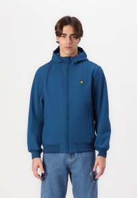 Blå zip-up huvtröja, slät tyg, två sidofickor, ribbade ärmslut och nederkant, med en liten gul logotyp på bröstet.