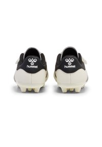 Pair of white and black soccer cleats with cleats visible on soles, viewed from the back, featuring hummel logo on heels.