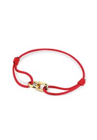 Bracelet en cordon tissé rouge avec un fermoir en métal doré et des nœuds à chaque extrémité. Texture lisse et design élancé.