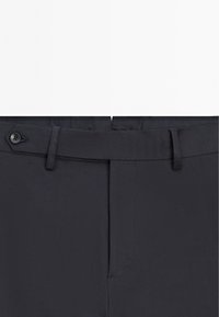 Marineblauwe broek met een gladde textuur; voorzien van een knoopsluiting en riemlussen. Rechte pasvorm met een vouw aan de voorkant.