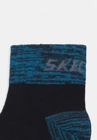 Must must have tekstureeritud sinise ja musta mustriga äär. Tootel on ülaosas hall logo, mis rõhutab erinevate kudumismaterjalide segu.