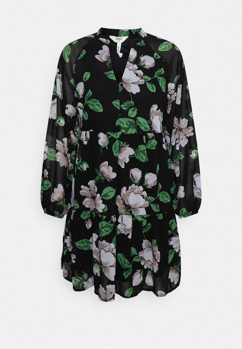 Robe noire avec manches longues transparentes, présentant des motifs floraux blancs et verts, un décolleté en V et une taille froncée pour plus de volume.