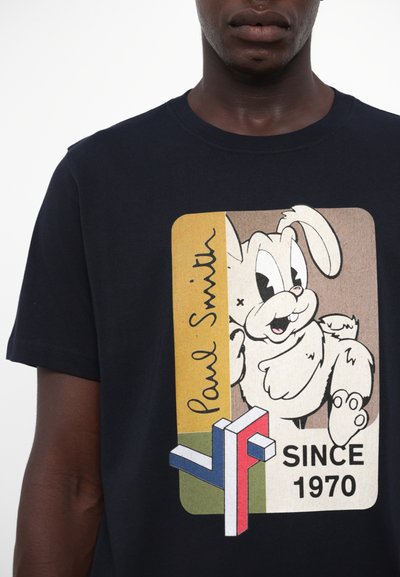 T-shirt en coton marine avec un graphique de lapin en cartoon, présentant des accents jaunes et bruns, le logo « Paul Smith » et le texte « SINCE 1970 ». 