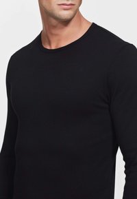 T-shirt nero a maniche lunghe realizzato in morbido cotone, con design a girocollo e silhouette aderente, senza motivi o dettagli visibili.