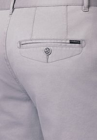 Jasnoszare eleganckie spodnie o teksturowanej tkaninie, z tylną kieszenią zapinaną na guzik oraz czarną metką z napisem "LANCERTO."