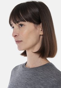 Szara koszulka z krótkim rękawem o okrągłym dekolcie, wykonana z miękkiego, teksturowanego materiału. Modelka prezentuje profil boczny z prostymi włosami.