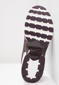 Suola di sneaker Nike con un distintivo motivo di trazione; gomma viola scuro con accenti bianchi e zone lisce. Superficie testurizzata per una migliore aderenza.