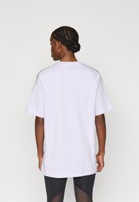 Bílé, volné tričko s krátkými rukávy, s kulatým výstřihem a kontrastními švy. Hladká bavlněná textura, minimalistický design.