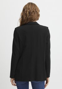 Svart blazer med skräddarsydd passform, slagkrage, enfingerknapp och rena linjer. Tillverkad av ett slätt, medeltungt tyg.