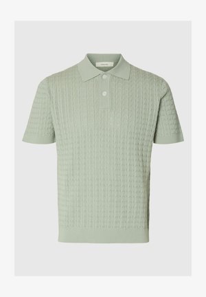 Hellgrünes, kurzärmeliges Strick-Poloshirt mit Zopfmuster, zwei Knöpfen sowie geripptem Kragen und Bündchen.