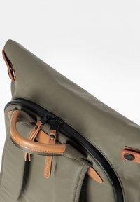Borsa verde oliva con un tessuto testurizzato, dotata di una cerniera nera, accenti in pelle marrone chiaro e un manico ad anello per un facile trasporto.
