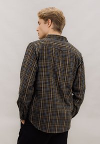 Brun og blå rutet skjorte med lange ermer, krage og kontrastfarget hvit søm, designet med en avslappet passform og bakstykke detaljer.