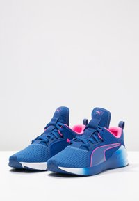 Blue athletic shoes with a breathable mesh upper, pink accents, and cushioned soles. Features a textured surface and a low-profile design.