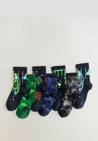 Sei coppie di calzini con vari motivi: camouflage verde, blu navy con schizzi, nero con gocce e grafiche multicolori, tutti con colori delle punte a contrasto.