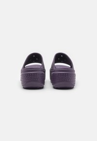 Paarse Crocs klompen met een gesloten achterkant, open teen, ventilatiegaten en een gestructureerde zool met verharde stippen voor grip.