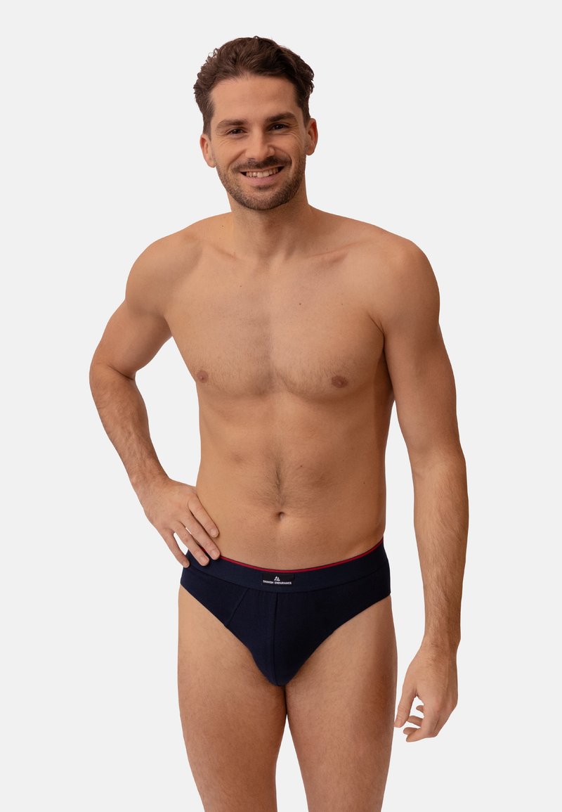 Marineblaue Herrenunterwäsche mit einem kontrastierenden roten Bund. Hergestellt aus weicher Baumwolle, mit einer engen Passform und nahtlosen Seiten für zusätzlichen Komfort.