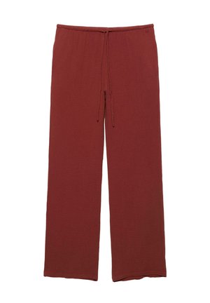 Pantalon large couleur rouille avec taille élastique et cordon de serrage à l'avant, fabriqué en tissu texturé.