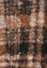 Υφασμα με υφή που παρουσιάζει ένα σγουρό μοτίβο σε αποχρώσεις του καφέ, μαύρου και κρεμ, με απαλό, αφράτο εμφάνιση.