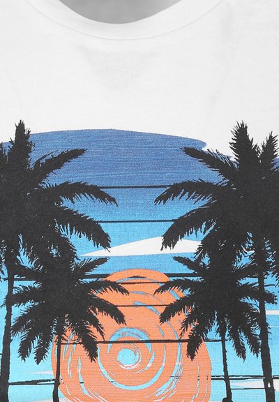 Witte T-shirt met een grafisch silhouet van palmboom tegen een gradient achtergrond van blauw en oranje, die een ondergang van de zon afbeeldt.