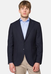 Granatowa marynarka wykonana z teksturowanej tkaniny, z dwiema kieszeniami z przodu, dwoma guzikami oraz dopasowanym krojem. Wnętrze ma gładkie wykończenie.