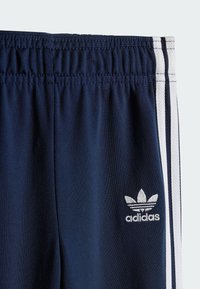 Mornarsko modri športni šort je z belimi stranskimi črtami, elastičnim pasom in šitimi detajli. Mali beli Adidasov logotip na spodnjem delu.