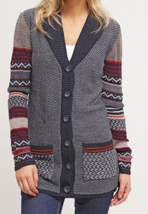 Donkergrijze cardigan met een gestructureerd lichaam, ribbelige sjalkraag, contrasterende patroonmouwen en twee zijzakken. Vijfknops sluiting.