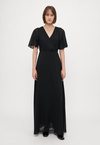 Black maxi dress with short, sheer flutter sleeves and a V-neckline. Flowing fabric with a gathered waist, floor-length design.