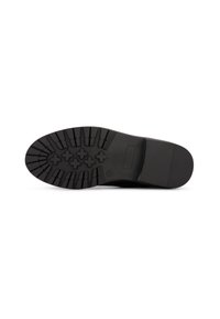 Suela de goma negra con un patrón de relieve texturizado, que presenta estrías y tacos en forma de cruz para una mejor adherencia y tracción.