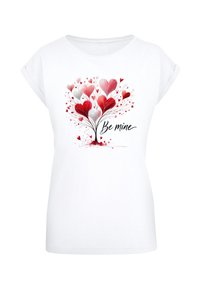 White short-sleeve t-shirt featuring a colorful design of red and white hearts forming a tree, with the text "Be mine" in a black script font.