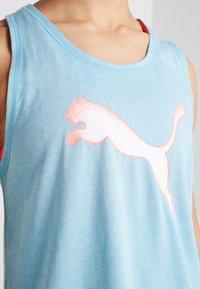 Canottiera azzurro chiaro realizzata in morbido tessuto, con un grande logo Puma bianco e rosa sul petto e un design classico senza maniche.