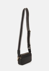 Schwarze, strukturiert wirkende Lederhandtasche mit rechteckiger Form, goldenen Reißverschlussdetails und einem schwarz-weißen, verstellbaren Tragegurt.