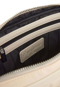 Beige handtas interieur met zwarte voering, voorzien van een ritszak en een leren label met de opdruk "Pepe Jeans London."