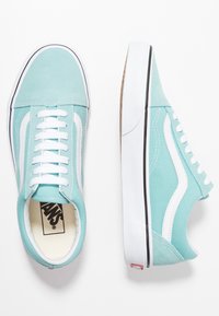 Baskets en toile bleu clair avec accents blancs, surface texturée et semelle en caoutchouc. Design classique à lacets avec un logo à l'intérieur.