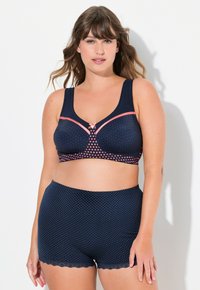 Marinblå bh med rosa prickar och kant, med en rosett som detalj. Kombinerad med matchande marinblå prickiga shorts, dekorerade med scalloped kanter.