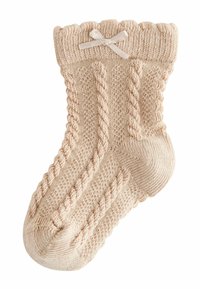 Calze in maglia beige con un design a cavo testurizzato, bordo arricciato e un piccolo fiocco decorativo sulla parte superiore. Materiale morbido e confortevole.