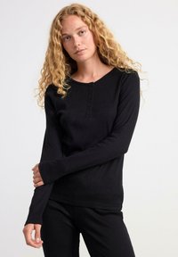 Černý dlouhý rukáv top ve ribbed textuře, s kulatým výstřihem a knoflíkovou légou. Měkká látka a přiléhavý silueta.