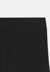 Svarta bomullsshorts med en tätt vävd textur. Har en slät elastisk midja och diskret sömdetalj längs kanterna.