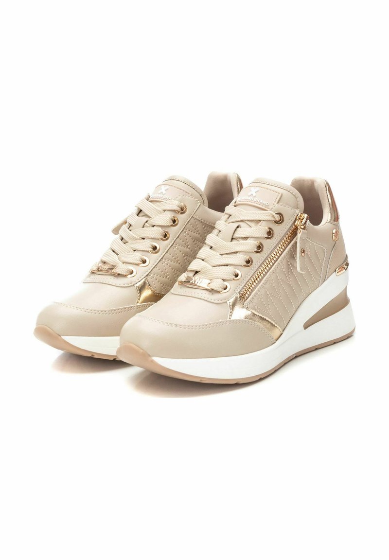 Sneakers beige con accenti testurizzati, cerniere in oro metallizzato e suole a zeppa bianche. Presentano lacci, colli imbottiti e dettagli con logo.