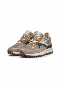 Un paio di scarpe da ginnastica casual beige, marroni e nere con lacci bianchi e suole in gomma scolpite angolate a destra su sfondo bianco.