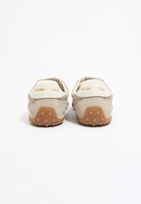 Lichtbeige suède schoenen met een gestructureerde rubberen zool. Voorzien van een witte hieltab met geëtst gouden lettertype. Rondvormig met een minimalistisch ontwerp.