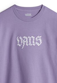 Camiseta púrpura con cuello redondo que presenta el logo "VANS" bordado en blanco en el centro. Tela suave con una textura lisa.