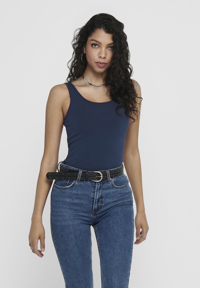 Navy blue tank top with a smooth texture, paired with high-waisted denim jeans and a studded black belt, featuring a silver buckle.