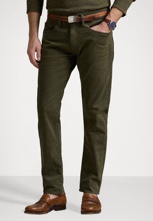 Chinos verde oliva con un diseño de pierna recta, elaborados en algodón. Combinados con mocasines de cuero marrón y un cinturón marrón con una hebilla de plata.