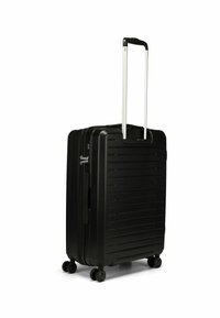 Valigia nera rigida con un design elegante e rigato, manico telescopico, quattro ruote e chiusura a cerniera per una conservazione sicura.