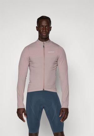 Veste de cyclisme rose clair avec zip intégral, manches longues et col haut ; associée à un short de cyclisme bleu foncé avec rembourrage.