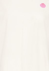T-shirt blanc cassé avec un petit motif de coquillage rose près de l'épaule droite en haut.