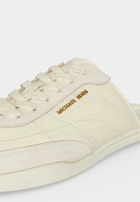 Ανοιχτόχρωμο λευκό sneaker από δέρμα με κορδόνια και χρυσό λογότυπο Michael Kors στο πλάι, με ραμμένα και υφασμένα στοιχεία σχεδίασης.