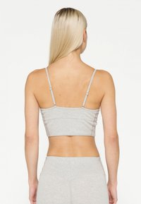 Grå cropped tank top med tynde stropper, lavet af blødt stof. Har et sømløst design og subtile syninger på ryggen.