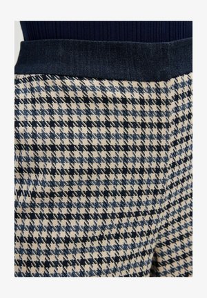Woven fabric pants with houndstooth pattern in navy and cream, featuring a dark denim waistband. Texture appears smooth with structured shape.