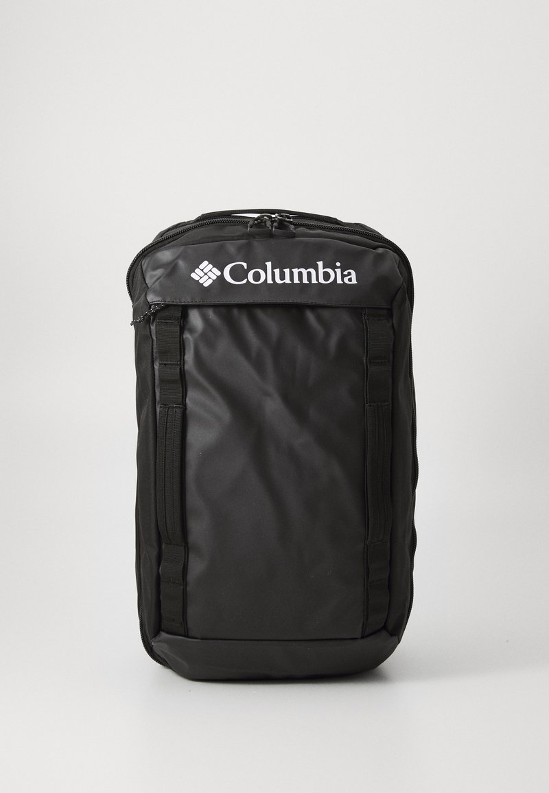 Mochila Columbia negra con textura acolchada, cierre superior con cremallera, correas laterales ajustables y un logotipo blanco prominente en el panel frontal.